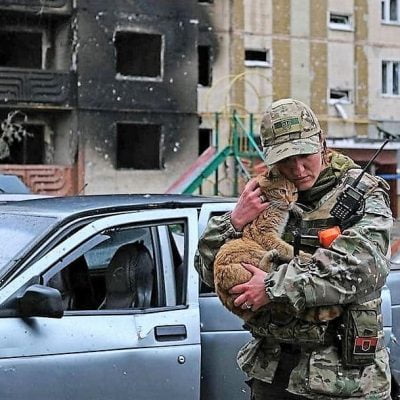 Ukrainian female soldier cuddles ginger tabby cat